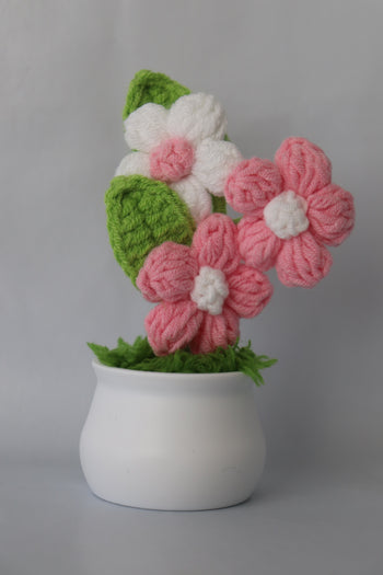 Knitted flowers in pink, white, and green on a gray background